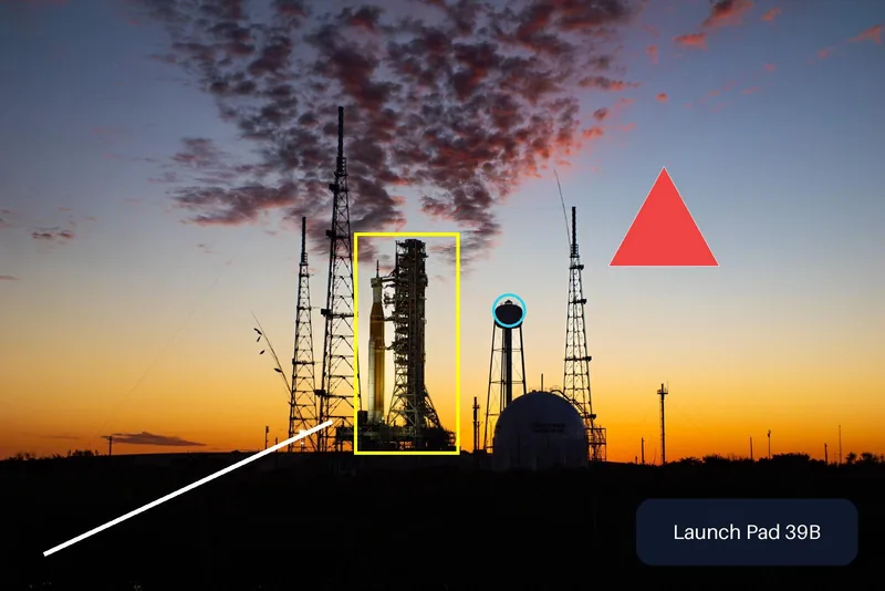 The launch pad photo with a yellow box around the rocket, a cyan circle on the water tower, a white line, a red triangle and a dark rounded label