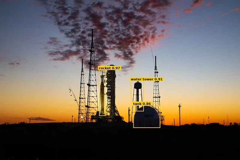 Launch pad photo with yellow labelled boxes around the rocket, a water tower and a tank